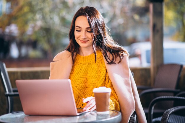 Geschäftsfrau, die an einem Computer arbeitet und Kaffee trinkt