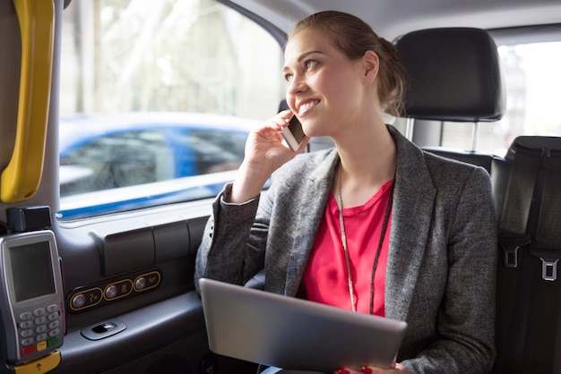 Geschäftsfrau, die arbeitet, während sie ein Taxi fährt