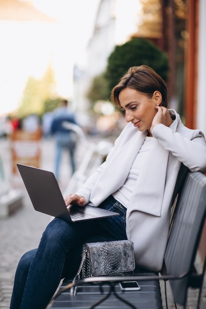 Geschäftsfrau, die auf einer bank sitzt und an einem computer arbeitet