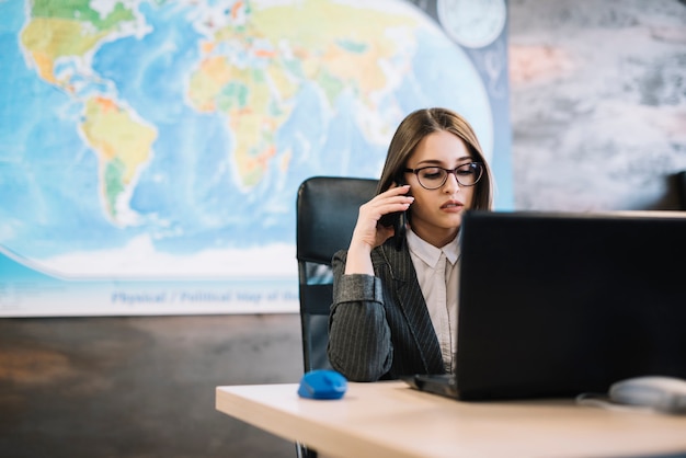 Kostenloses Foto geschäftsfrau, die bei tisch telefonisch spricht