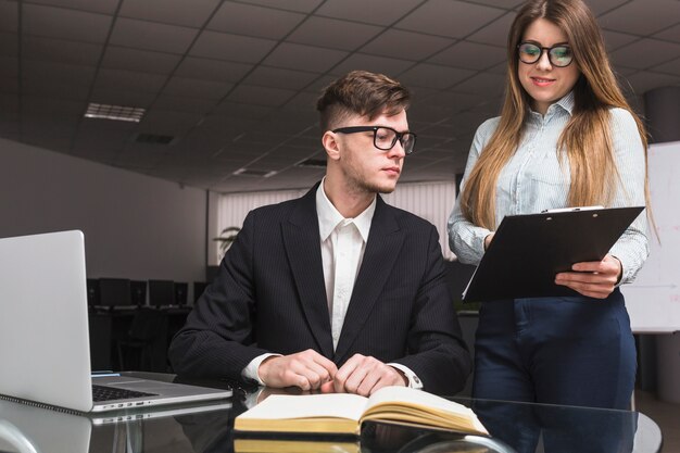 Geschäftsfrau, die dem männlichen Kollegen Dokument im Büro zeigt