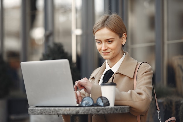 Geschäftsfrau, die draußen mit laptop und kaffee steht