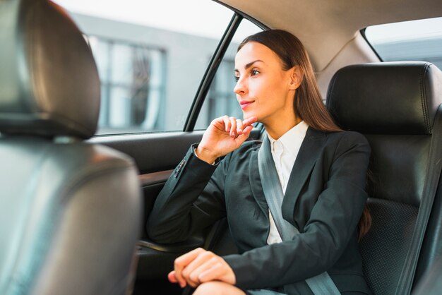 Geschäftsfrau, die durch Fenster beim Reisen mit dem Auto schaut