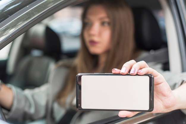 Geschäftsfrau, die einen Smartphone im Auto zeigt