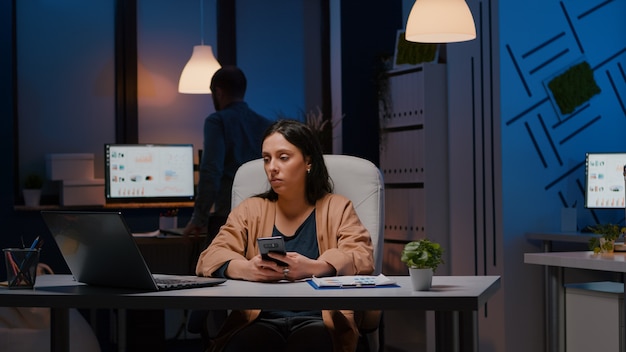 Geschäftsfrau, die im Büro eines Startup-Unternehmens arbeitet, das am Schreibtisch sitzt