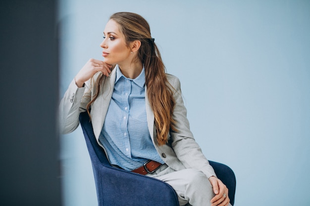 Geschäftsfrau, die im Stuhl an einem Büro sitzt