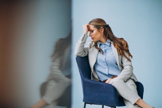 Geschäftsfrau, die im Stuhl an einem Büro sitzt