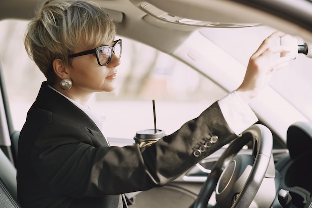 Geschäftsfrau, die in einem Auto sitzt und einen Kaffee trinkt