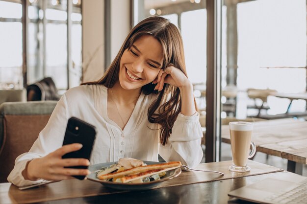 Geschäftsfrau, die in einem Café zu Mittag isst und am Computer arbeitet