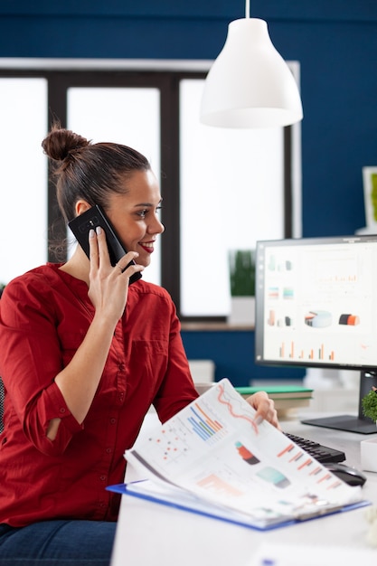 Geschäftsfrau, die mit dem Smartphone am Schreibtisch telefoniert