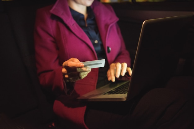 Geschäftsfrau, die Online-Shopping auf Laptop mit Kreditkarte tut