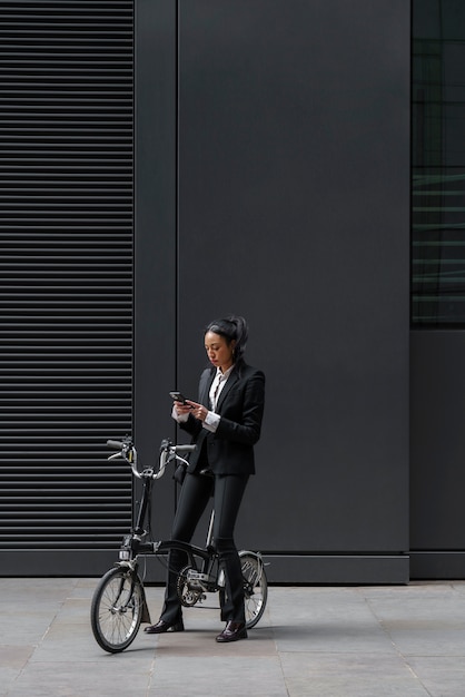 Geschäftsfrau, die Smartphone auf einem Fahrrad überprüft