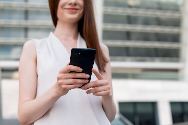 Kostenloses Foto geschäftsfrau, die smartphone in der straße verwendet