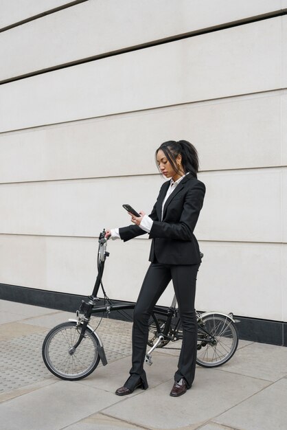 Geschäftsfrau, die Smartphone mit einem Fahrrad überprüft