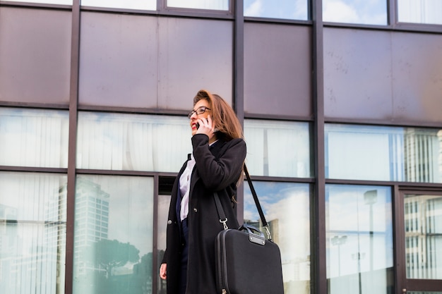 Geschäftsfrau, die telefonisch auf Gebäudehintergrund spricht