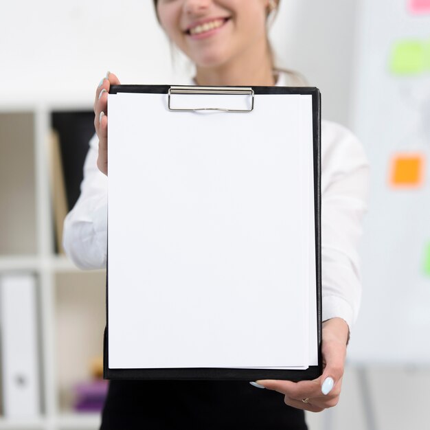 Geschäftsfrau, die Weißbuch auf schwarzem Klemmbrett zeigt
