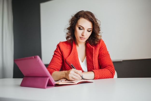 Geschäftsfrau im Büro, das mit digitaler Tablette und anderen Dokumenten arbeitet.