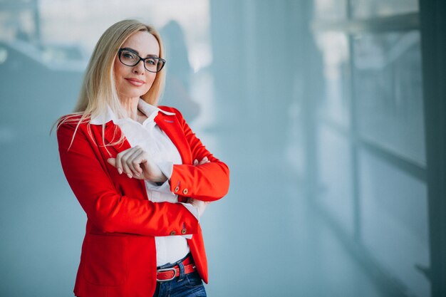 Geschäftsfrau in der roten Jacke lokalisiert im Büro