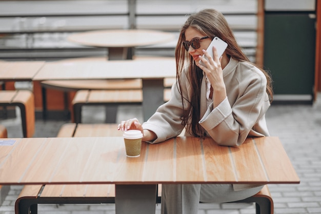 Geschäftsfrau in einem Café trinkendes coffe, unter Verwendung des Telefons