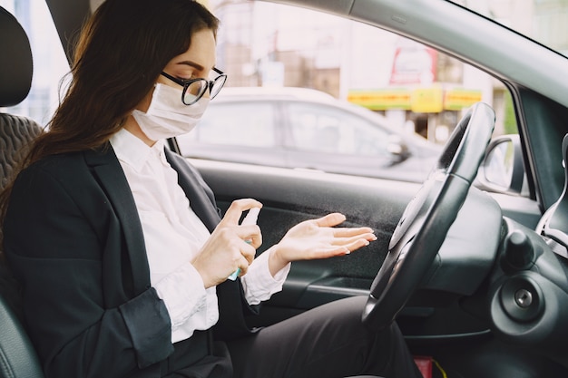 Geschäftsfrau in einer schwarzen Maske, die in einem Auto sitzt