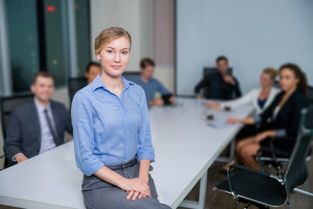 Geschäftsfrau mit den Arbeitern an einem Tisch sitzen hinter