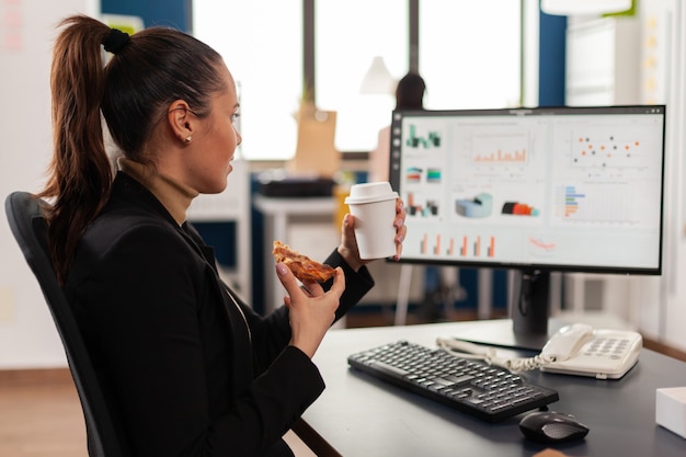 Geschäftsfrau mit Essensbestellung auf dem Schreibtisch während der Mittagspause, die im Büro des Unternehmens arbeitet?