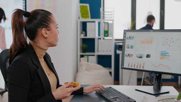 Geschäftsfrau mit Essensbestellung auf dem Schreibtisch während der Mittagspause, die im Büro des Unternehmens arbeitet?