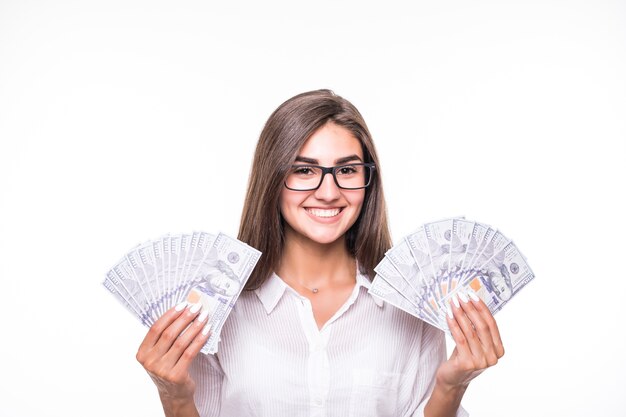 Geschäftsfrau mit langen braunen Haaren in Freizeitkleidung hält viele Banknoten über Weiß