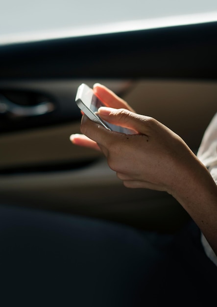 Geschäftsfrau überprüft ihr Telefon während einer Autofahrt
