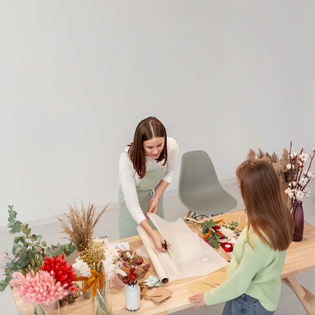 Geschäftsfrauen, die am Blumenladen mit Plänen arbeiten