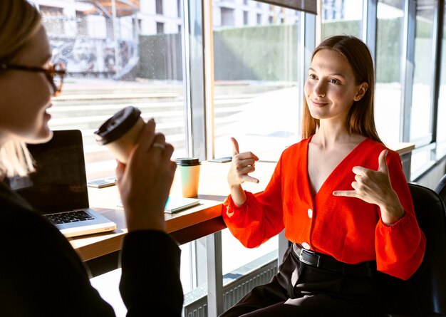 Geschäftsfrauen, die Gebärdensprache bei der Arbeit beim Kaffee verwenden