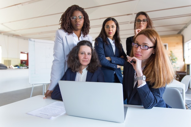 Geschäftsfrauen, die Laptop verwenden und Kamera betrachten