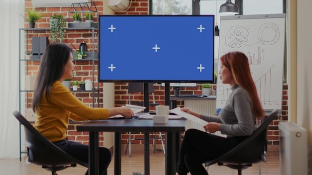 Geschäftsfrauen, die leeren Kopienraumbildschirm im Startbüro analysieren. Arbeitskollegen, die Chroma-Key-Hintergrund mit isoliertem Modell und leerer Vorlage auf dem Monitor betrachten. Zusammenarbeit