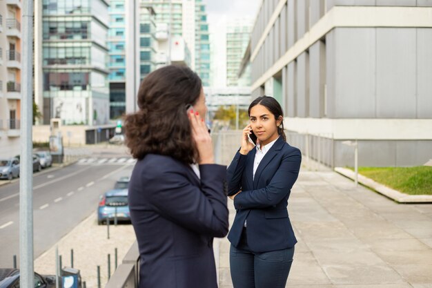 Geschäftsfrauen, die mit Smartphones auf der Straße sprechen