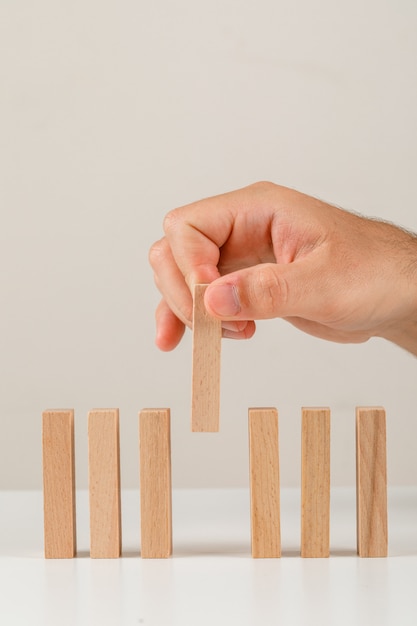 Geschäftskonzept auf Seitenansicht des weißen Hintergrunds. Hand, der Holzblock auf Linie setzt.