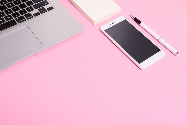 Geschäftskonzept: bürodesktop mit laptop, handy. rosa hintergrund.