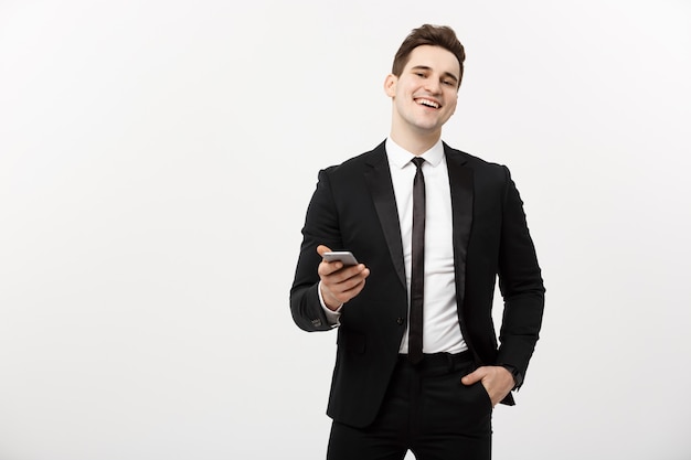 Geschäftskonzept: Glücklicher junger Geschäftsmann im intelligenten Anzug, der SMS auf grauem Hintergrund schreibt