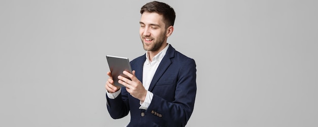 Geschäftskonzept-Porträt-hübscher Geschäftsmann, der digitale Tablette mit dem lächelnden selbstbewussten Gesicht weißer Hintergrund-Kopien-Raum spielt