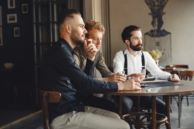 Geschäftsleute in Verhandlungen. Männer mit Alkohol sitzen am Tisch. Freunde reden.