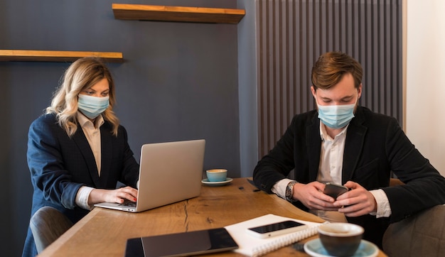 Kostenloses Foto geschäftsleute sprechen über ein neues projekt, während sie medizinische masken tragen