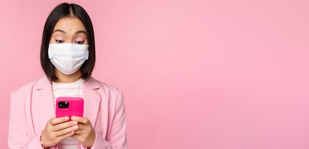 Geschäftsleute und Covid-Konzept Junge asiatische Geschäftsfrau in Anzug und medizinischer Gesichtsmaske mit smar