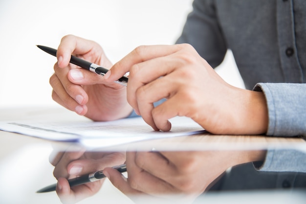 Geschäftsmann am Tisch in der Hand mit Stift sitzt