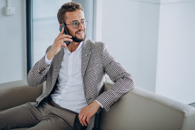 Geschäftsmann, der auf einem Sofa sitzt und Telefon benutzt