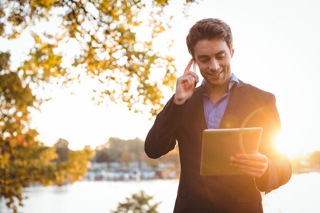 Geschäftsmann, der auf Handy spricht, während digitales Tablett verwendet wird