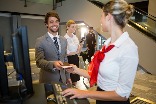 Kostenloses Foto geschäftsmann, der dem weiblichen personal am check-in-schalter seine bordkarte gibt