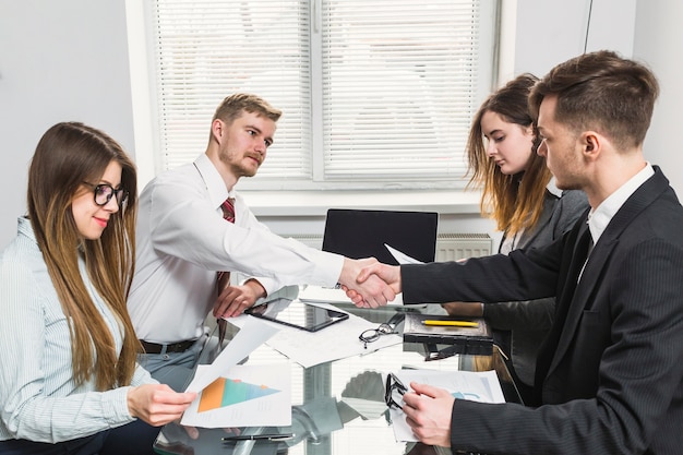 Kostenloses Foto geschäftsmann, der hand mit seinem kollegen im büro rüttelt