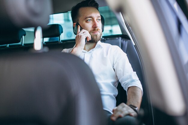 Geschäftsmann, der in einem Auto unter Verwendung des Telefons sitzt