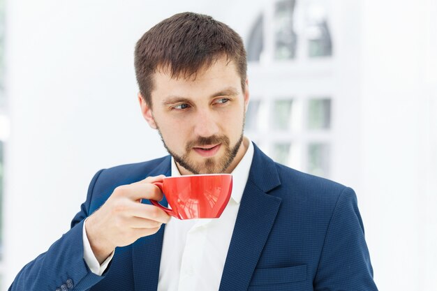 Geschäftsmann, der Kaffeepause hat, hält eine Tasse