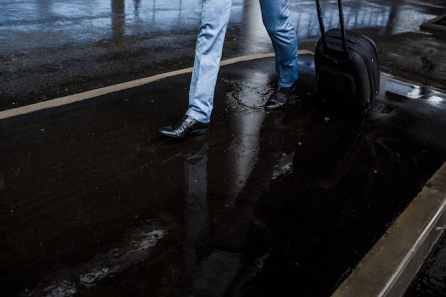 Geschäftsmann, der Koffer hält, der im Regen geht