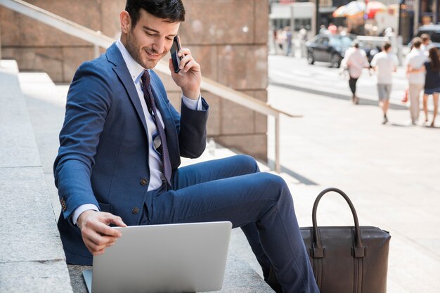 Geschäftsmann, der Laptop verwendet und am Telefon spricht